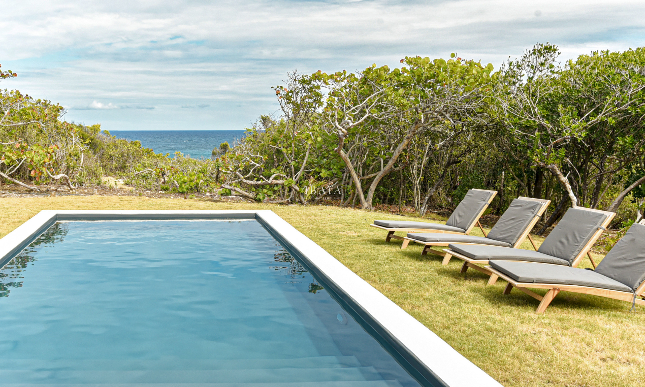 Ocean and pool view with comfortable wooden sunbeds in Marie Galante