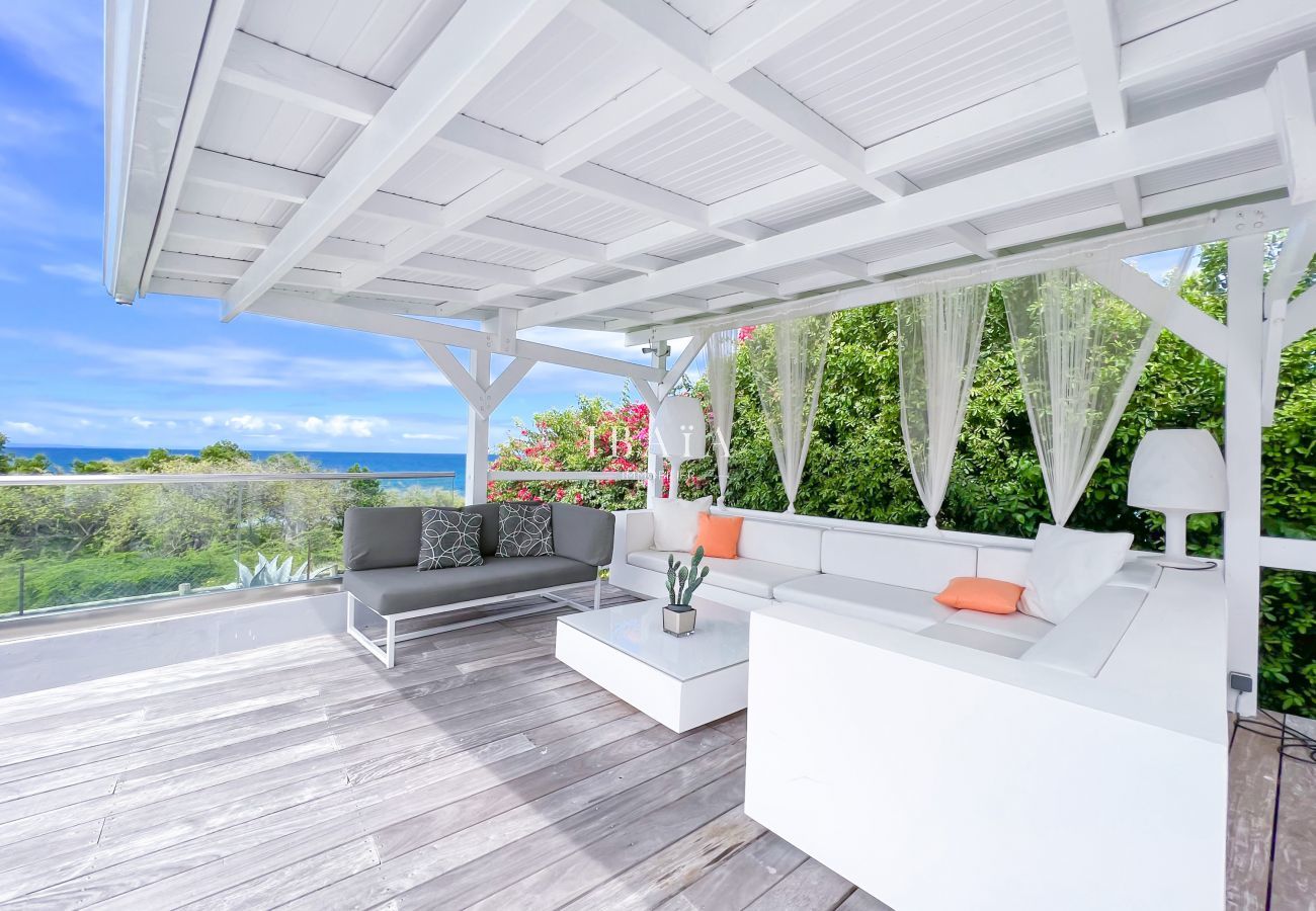 View of the garden furniture under the patio on a wooden terrace overlooking the sea in our top-of-the-range villa in the West Indies