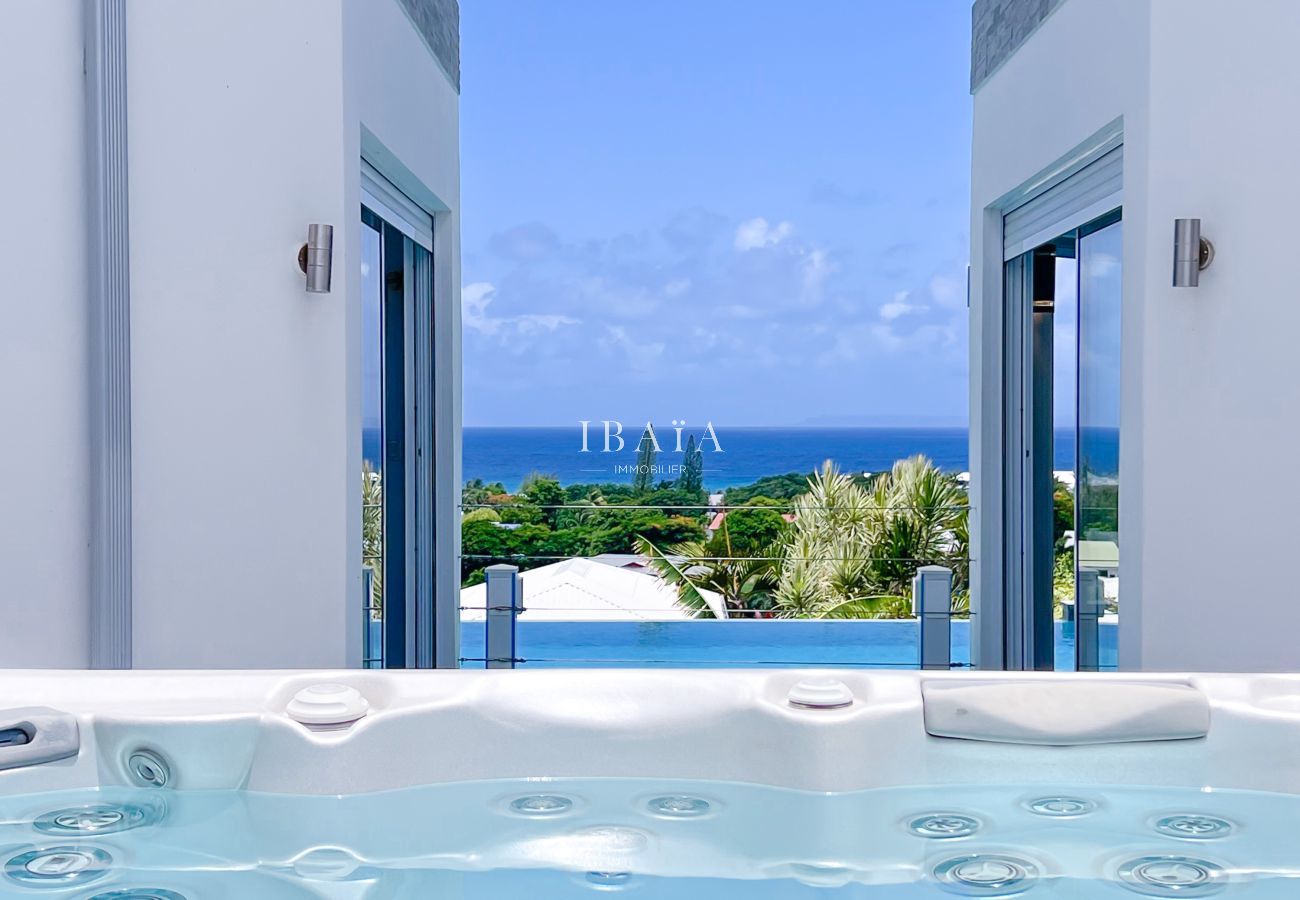 Outdoor hot tub between open doors overlooking the sea