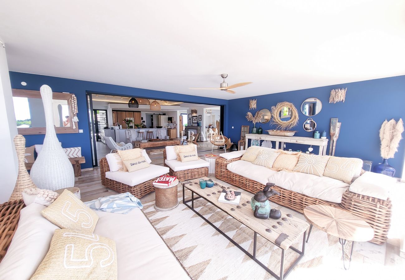 Spacious living room with blue walls, rattan furniture and boho-chic decoration