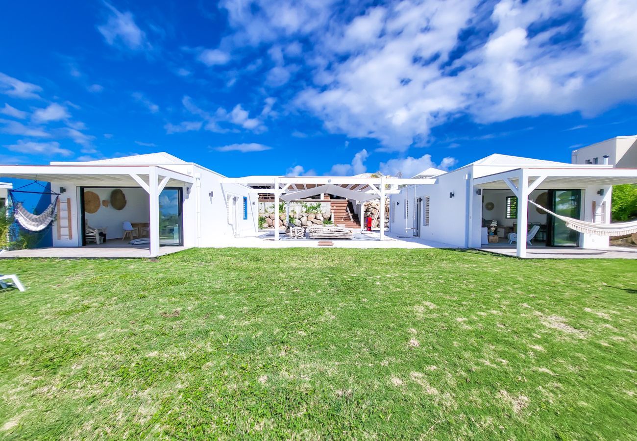 Set of white bungalows with hammocks and central green space under blue sky