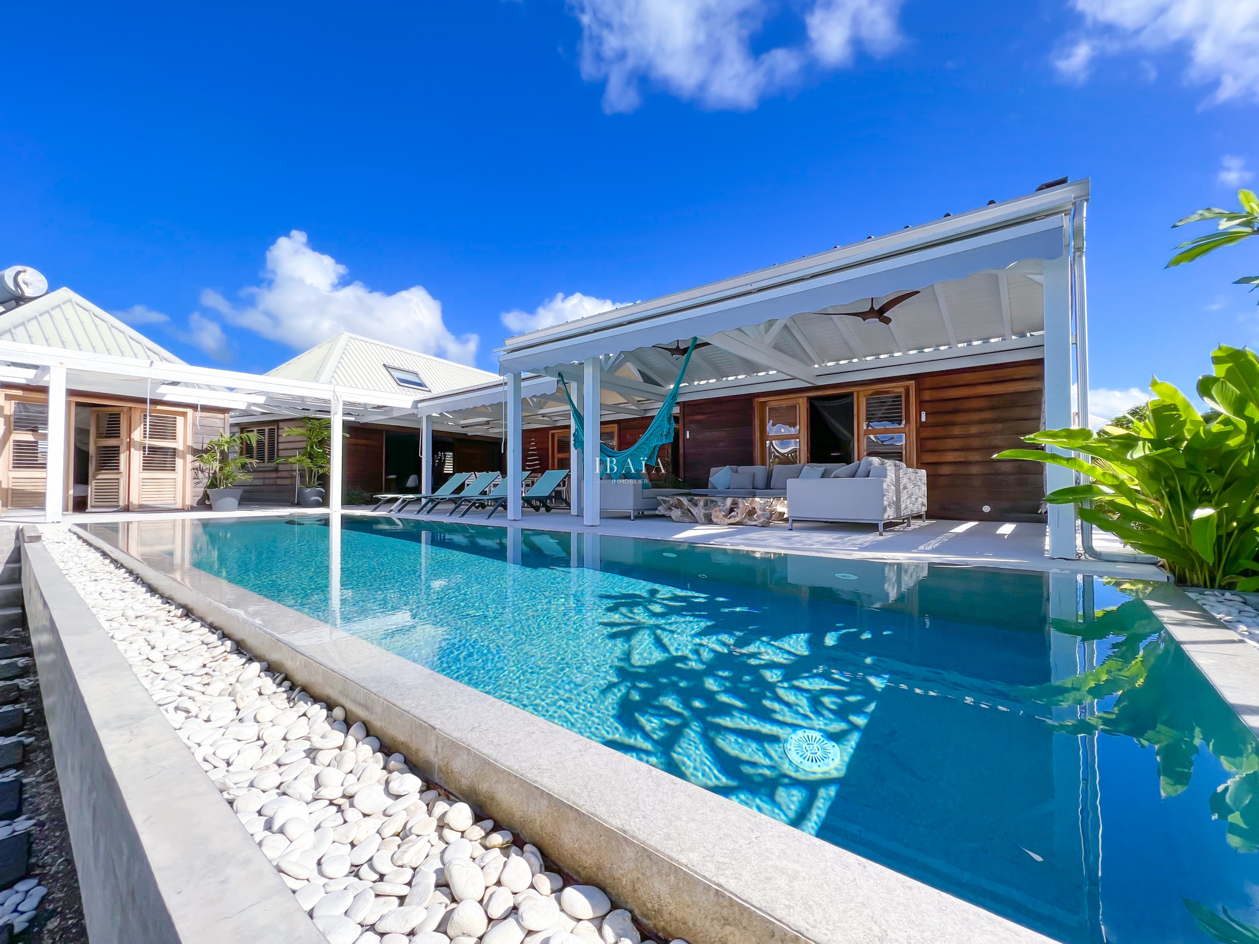 Piscina de espejos frente a la terraza equipada con tumbonas y muebles de jardín