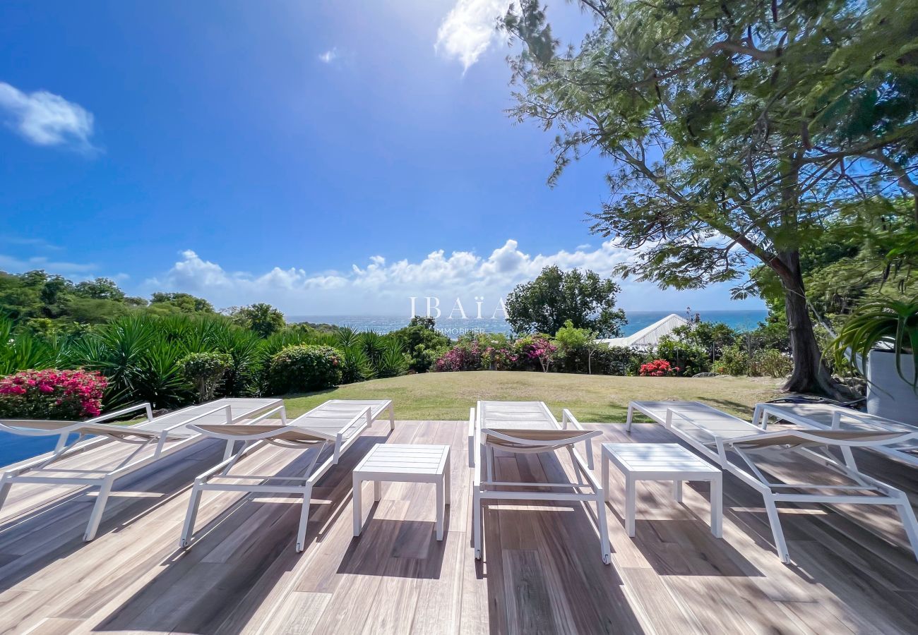 Vista al océano desde terraza con tumbonas y jardín tropical