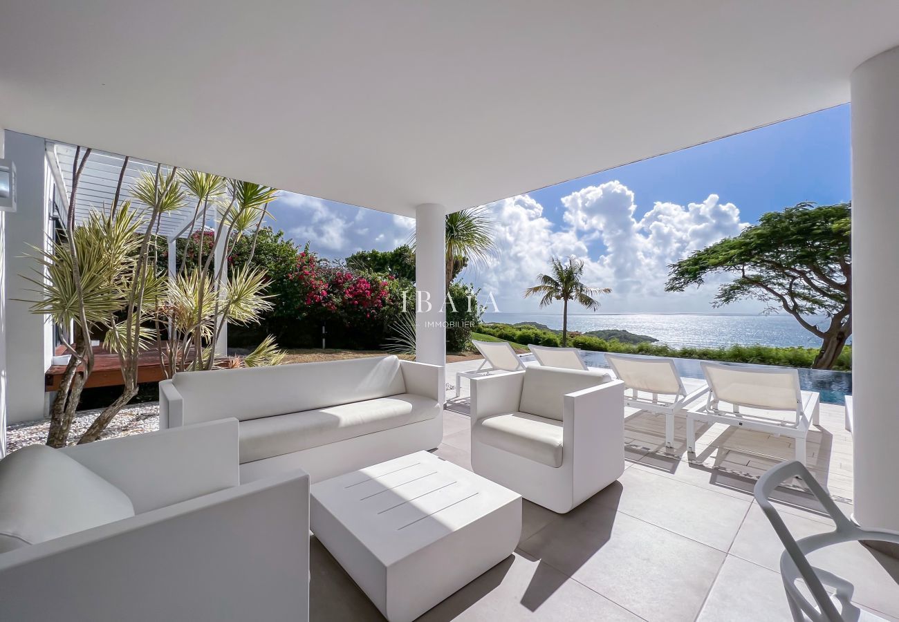 Salón exterior blanco con vistas a la piscina y al mar