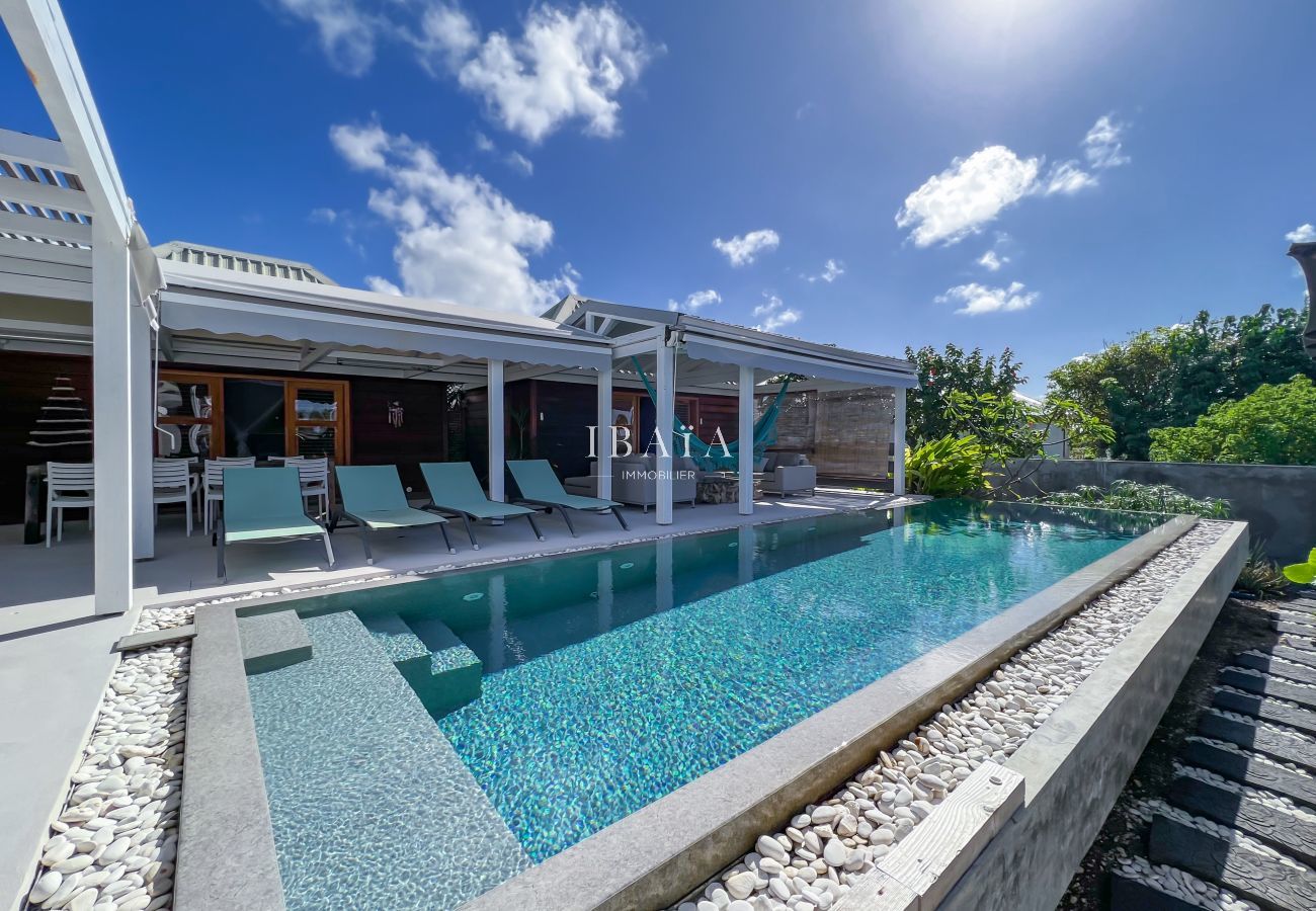 Magnífica piscina de espejos al borde de la terraza equipada con muebles de jardín, tumbonas y mesa de comedor