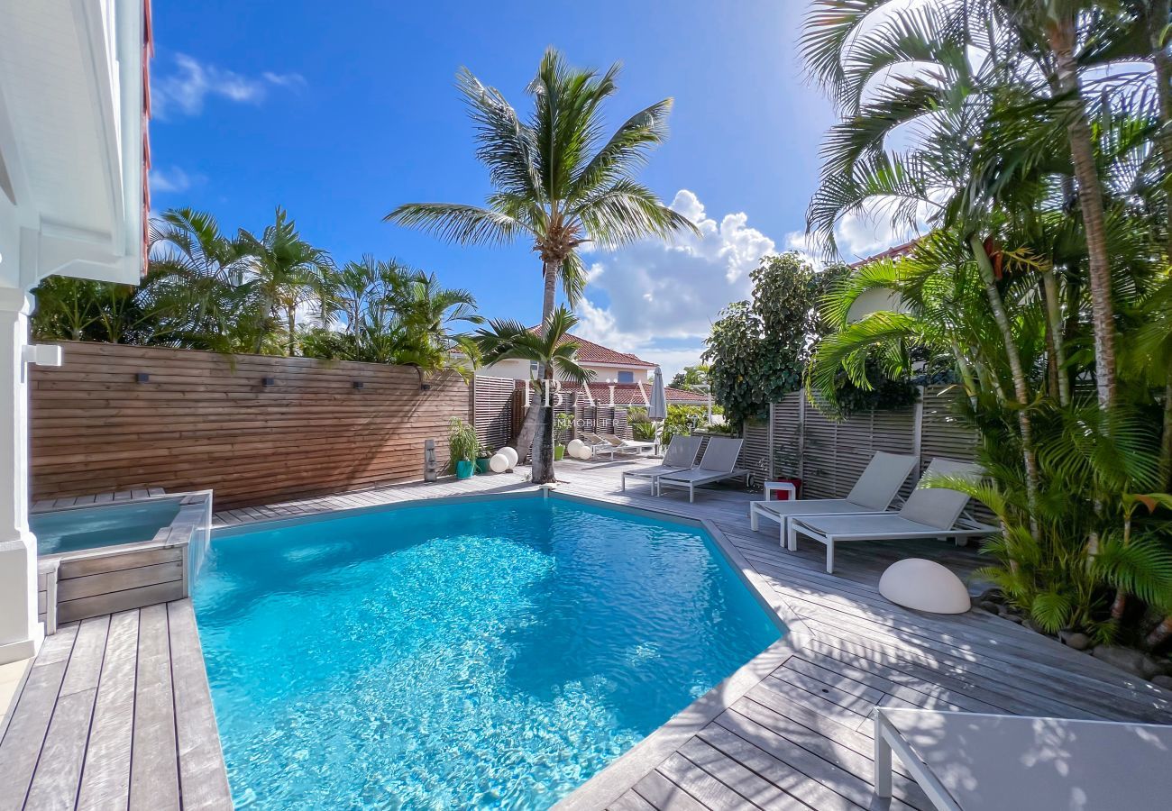 Piscina de agua salada y terraza de madera con tumbonas y jardín tropical