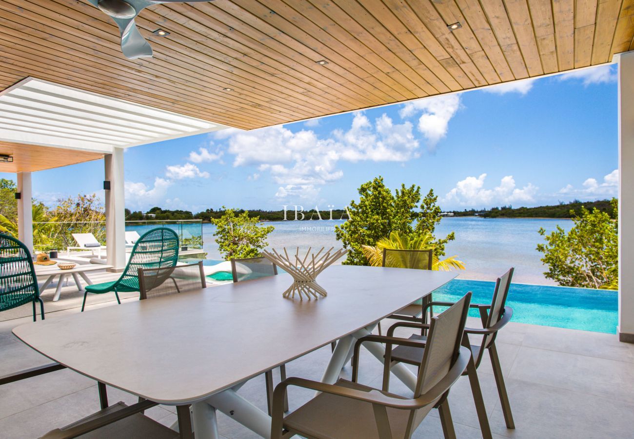 Vista del comedor en la terraza con vistas a la piscina y el mar al fondo en nuestra villa de alta gama en las Antillas.