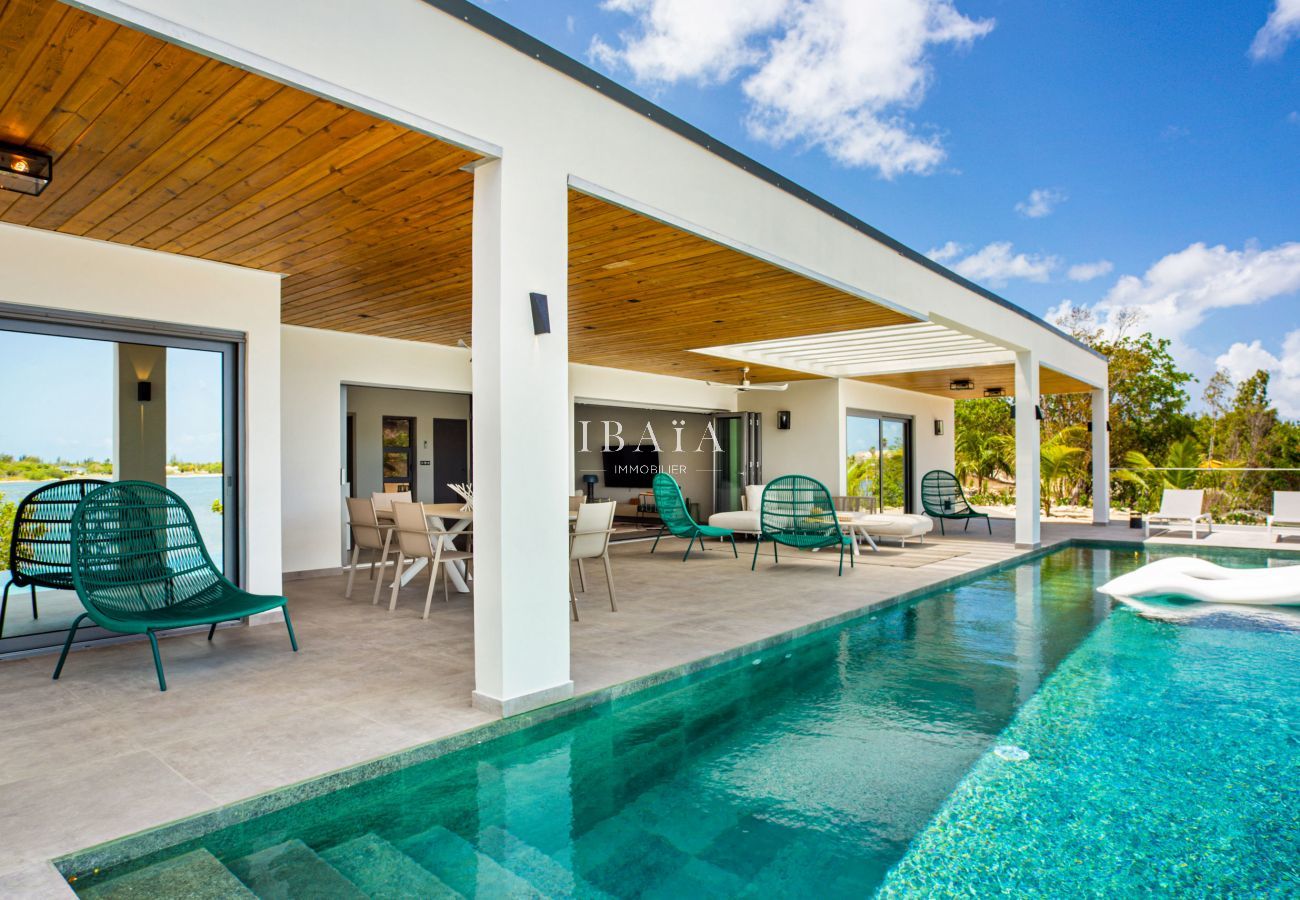 Vista de la magnífica piscina rectangular infinita con azulejos de cerámica, rodeada de una gran terraza con zona de estar y comedor en nuestra villa 