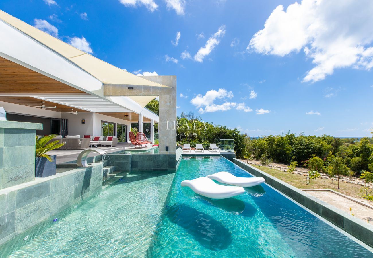 Piscina infinita con tumbonas flotantes y vistas al jardín tropical - Villa de lujo en las Antillas