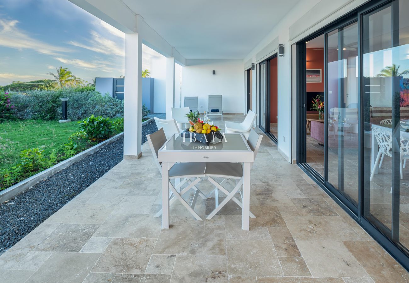 Amplia terraza de una casa moderna con vista al jardín y puerta corrediza de vidrio.