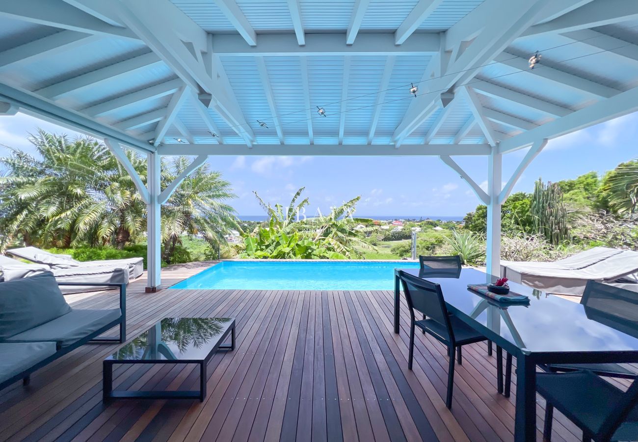 Vista de una terraza de madera con piscina y vegetación exuberante