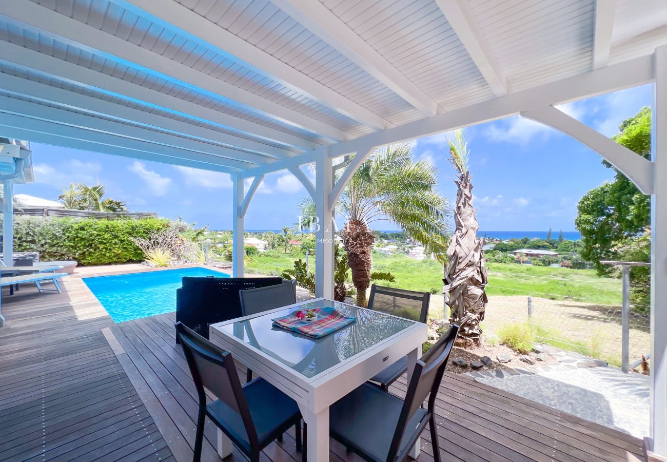 Patio al aire libre con mesa de comedor, piscina y vistas al océano