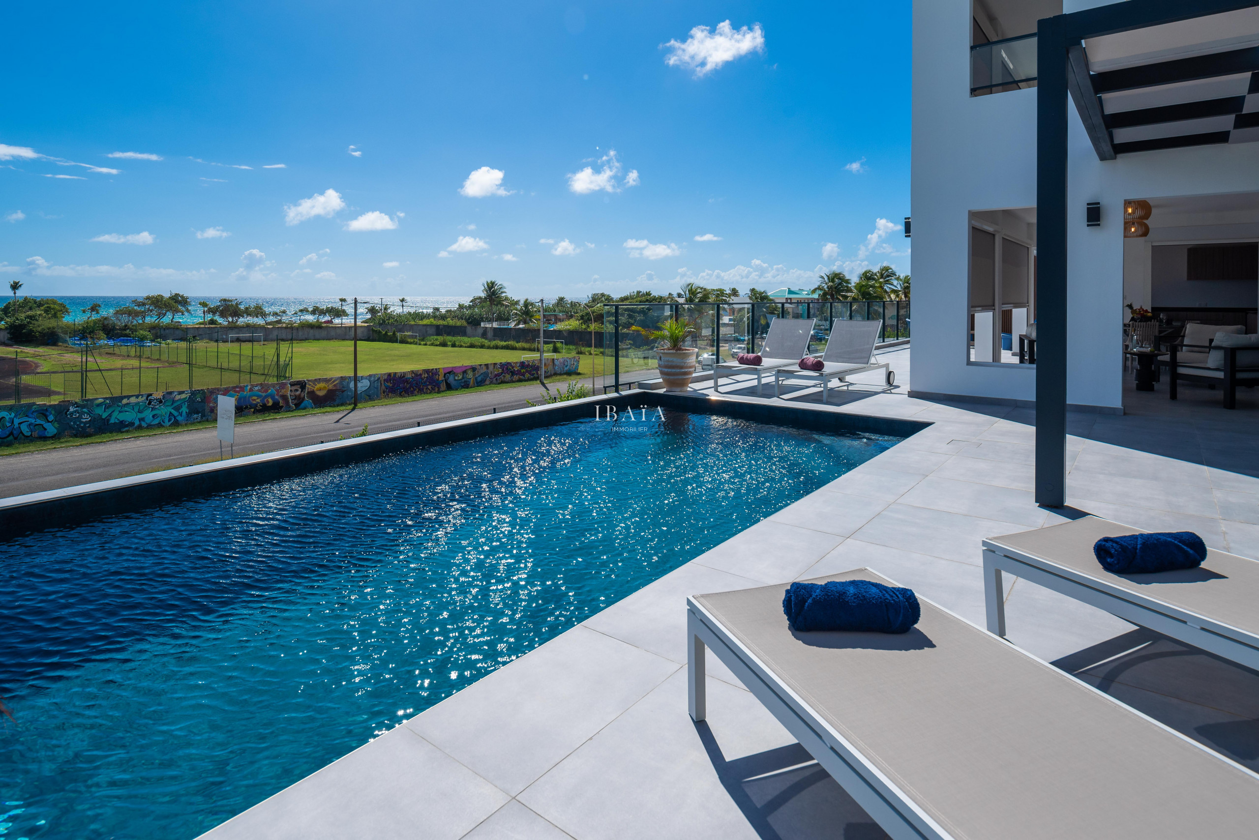 Piscine luxueuse d'une maison moderne avec vue sur l'océan et mur graffité.