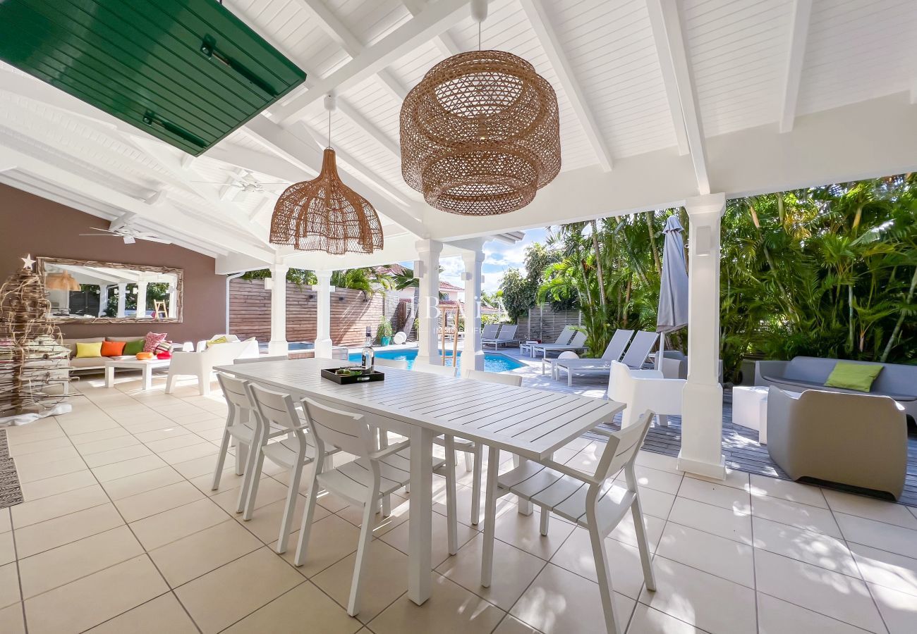 Large table à manger pour 8 personnes en bordure de la terrasse en bois avec vue sur la piscine au sel