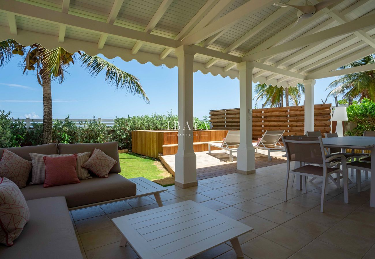 Vue de la terrasse avec salon d'extérieur et table à manger offrant une vue sur la mer et la piscine de notre villa haut de gamme aux Antilles.