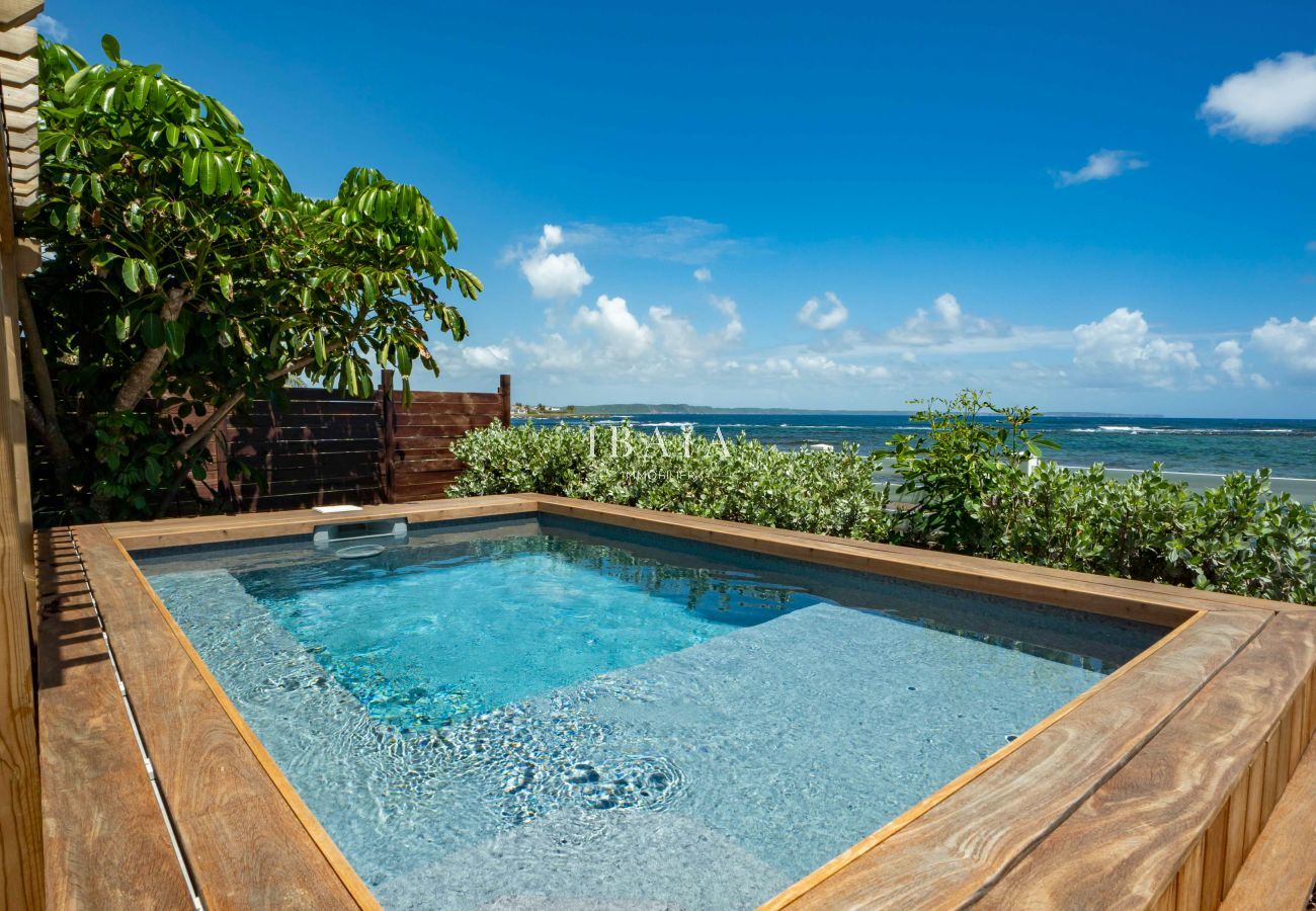 Vue de la piscine en bord de mer avec un coffrage en bois de notre villa haut de gamme aux Antilles