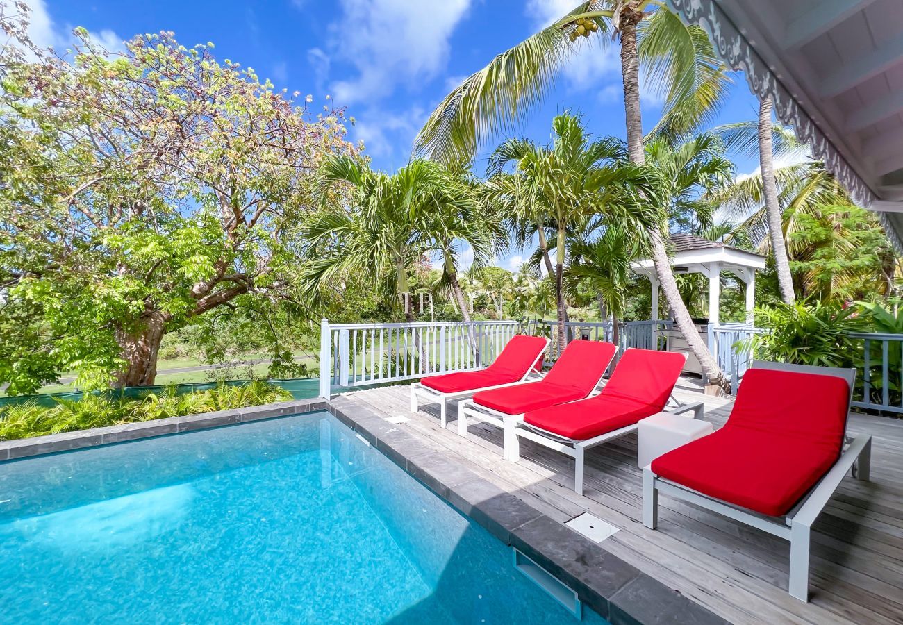 Transats rouges en bord de piscine sur terrasse en bois - Villa haut de gamme aux Antilles