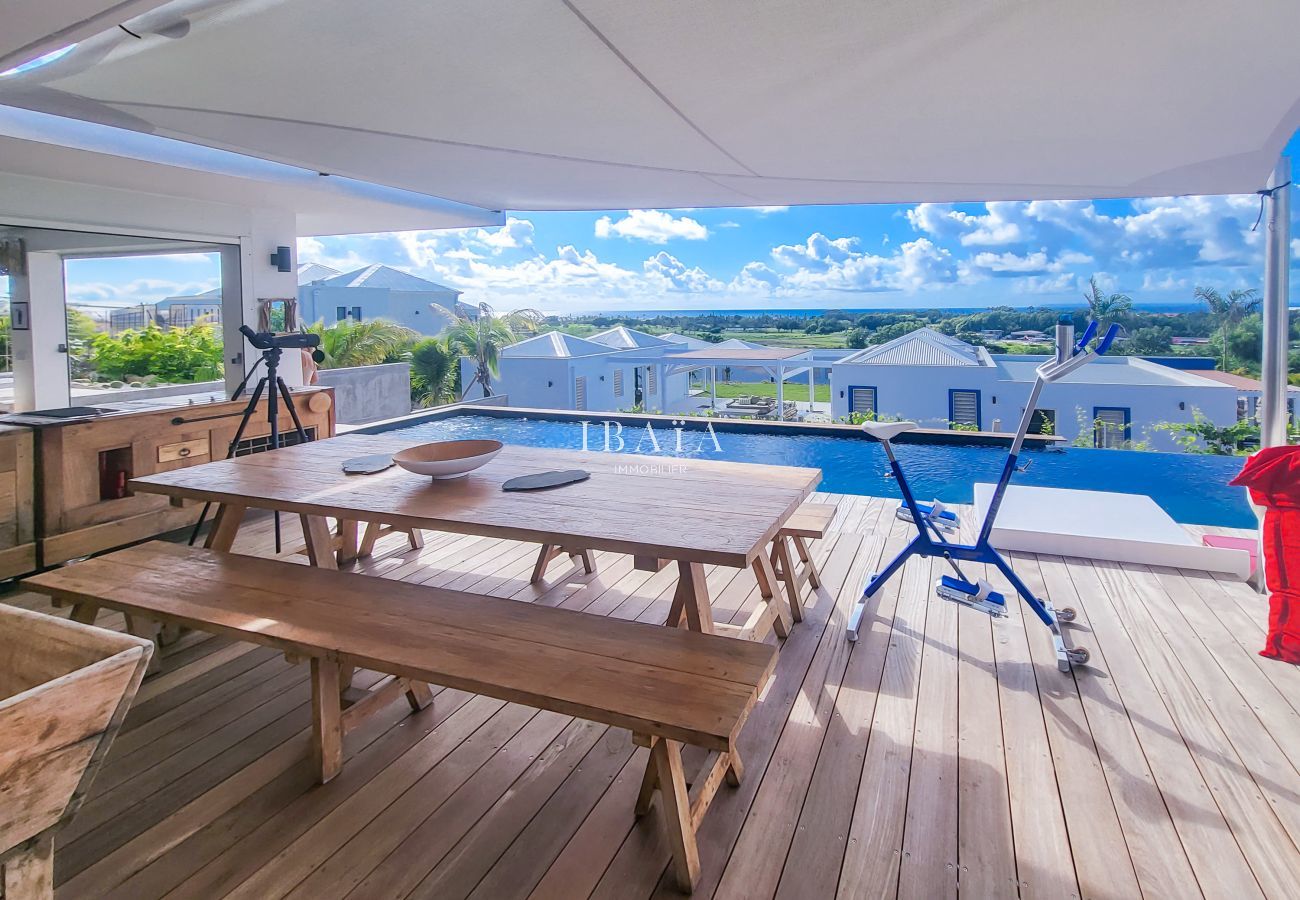 Grande table à manger, chaises design, vue sur terrasse ensoleillée